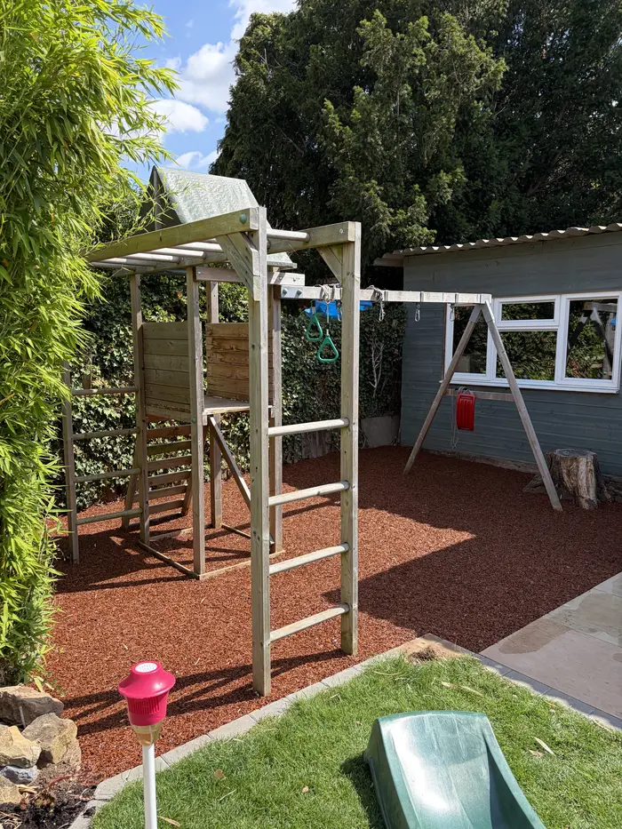 Red rubber mulch playground surfacing around a climbing frame, by A&P Resin