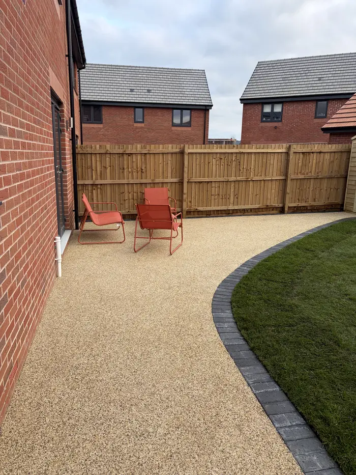 Beige resin bound garden patio with a curved lawn edge, by A&P Resin