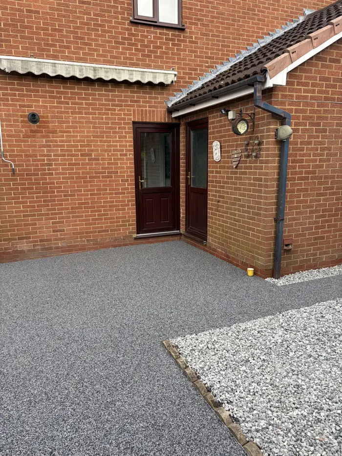 Grey resin bound patio with gravel border at the back of a house, by A&P Resin