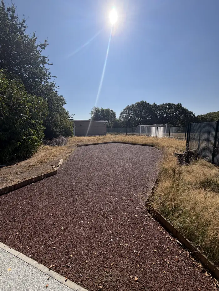 Red rubber mulch path beside a school field, by A&P Resin