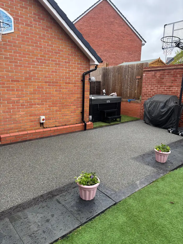Grey resin bound patio with artificial grass and potted plants, by A&P Resin