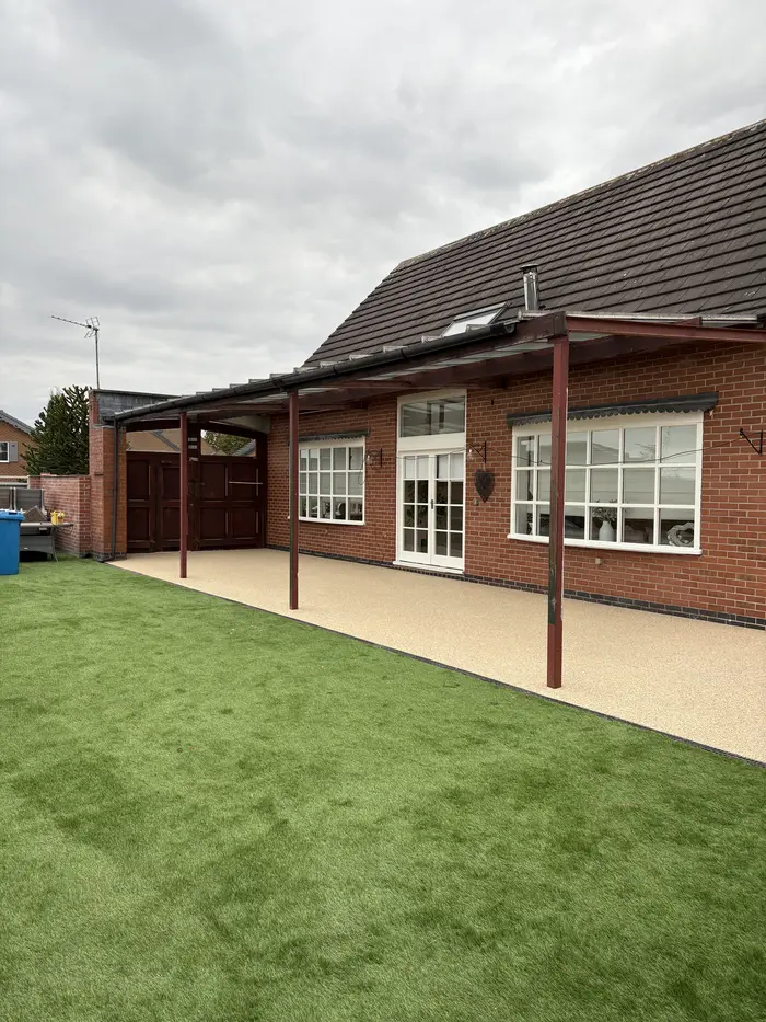 Artificial grass and cream resin bound patio behind a house, by A&P Resin